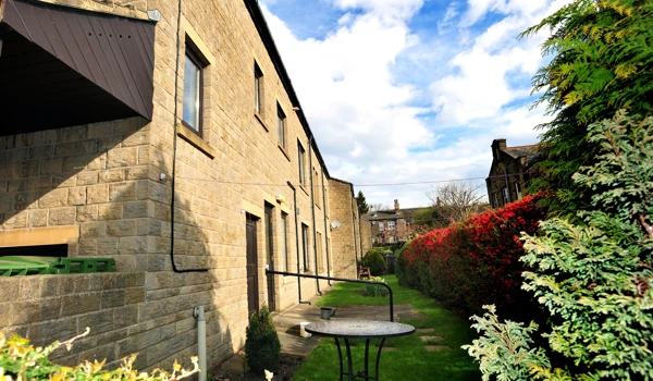 The rear of Abbeyfield House with a table in the garden, independent living in Pudsey
